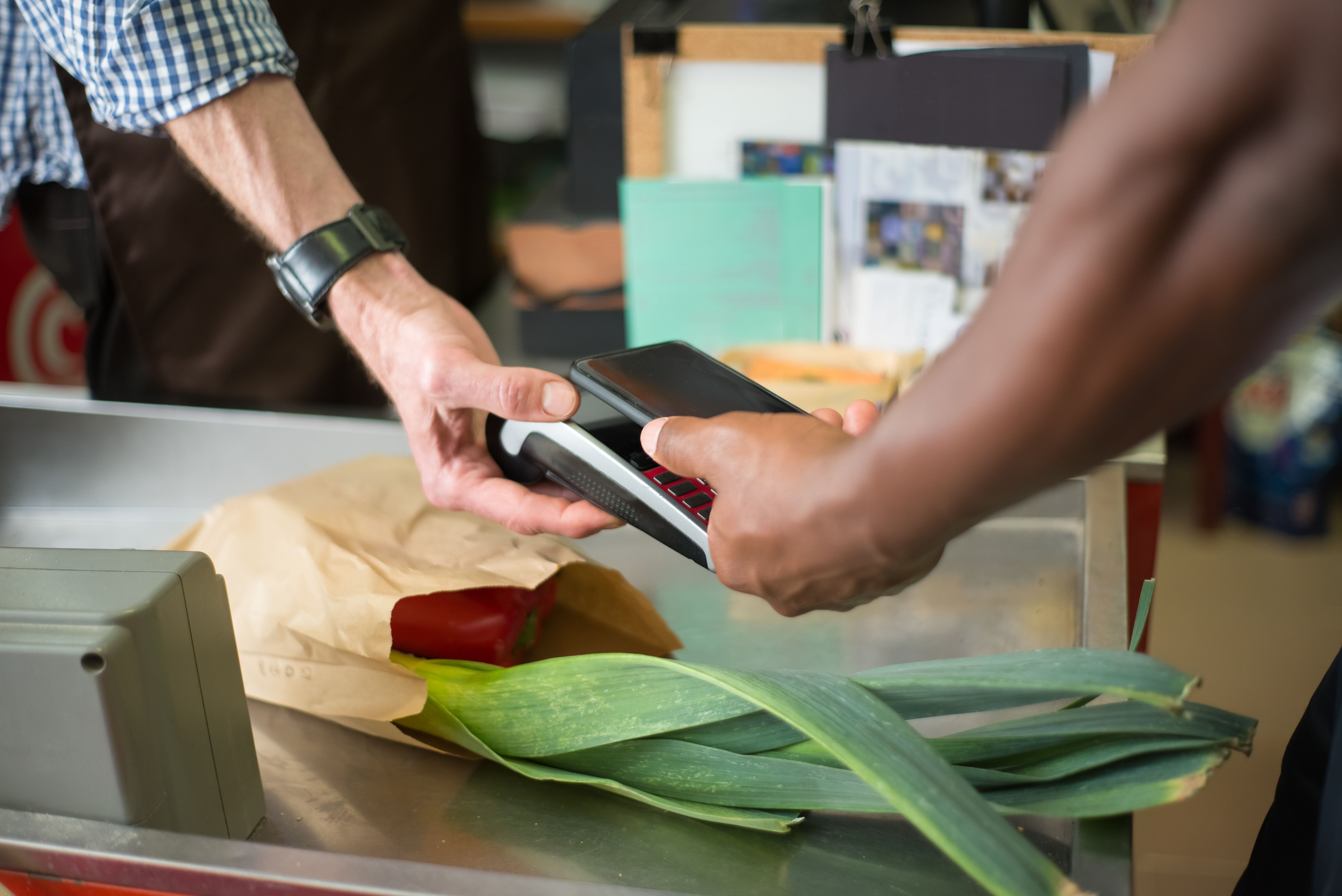 A person using a phone to pay at a café counter,.