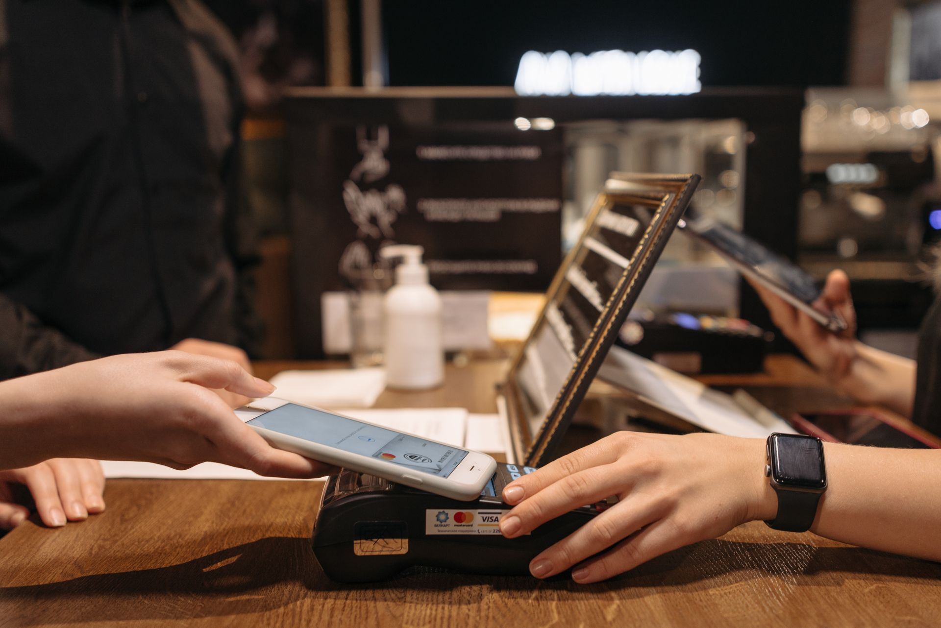 A person using a phone to pay at a café counter