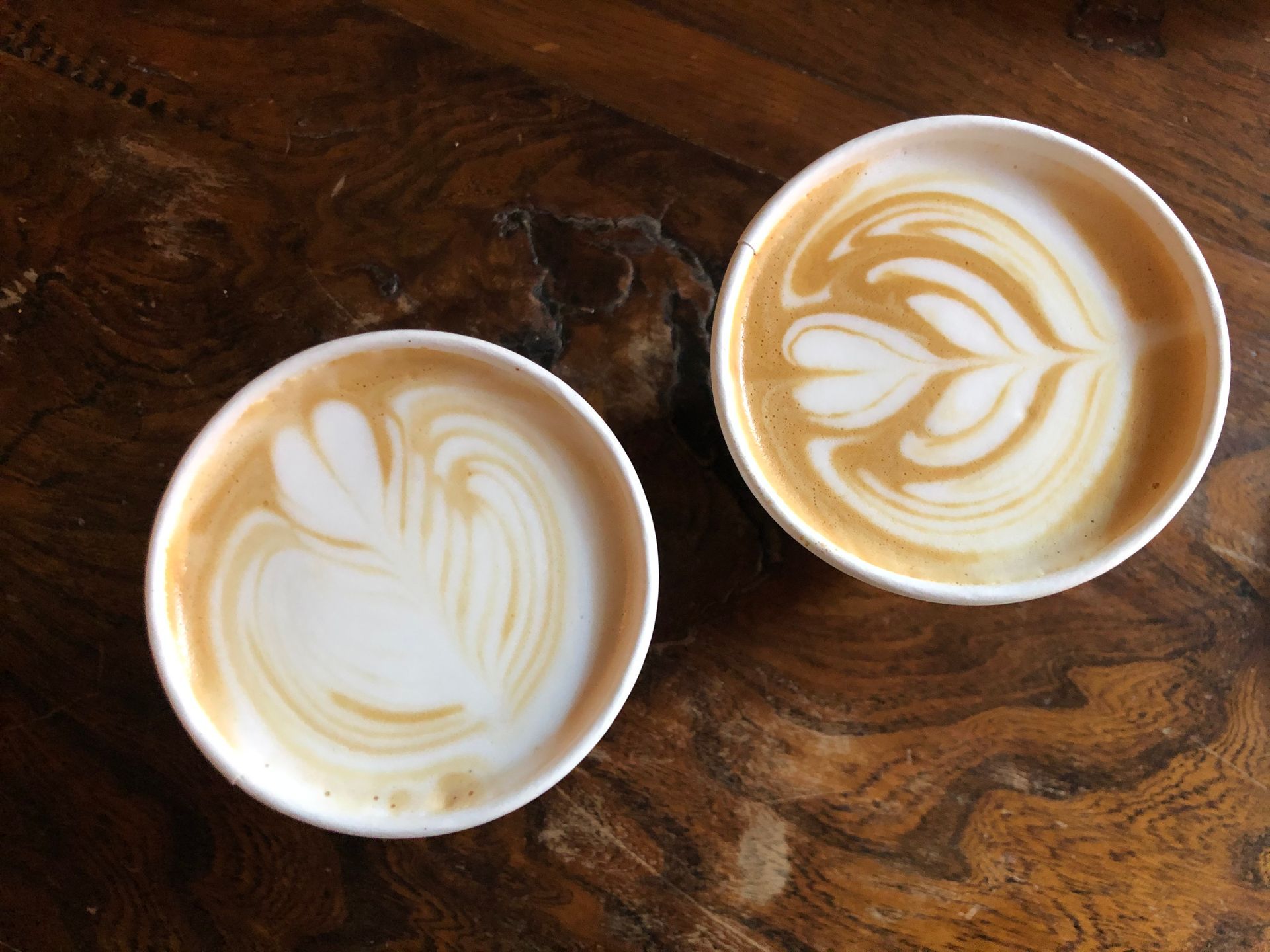 Two cups placed opposite each other on a plain table, seen from above