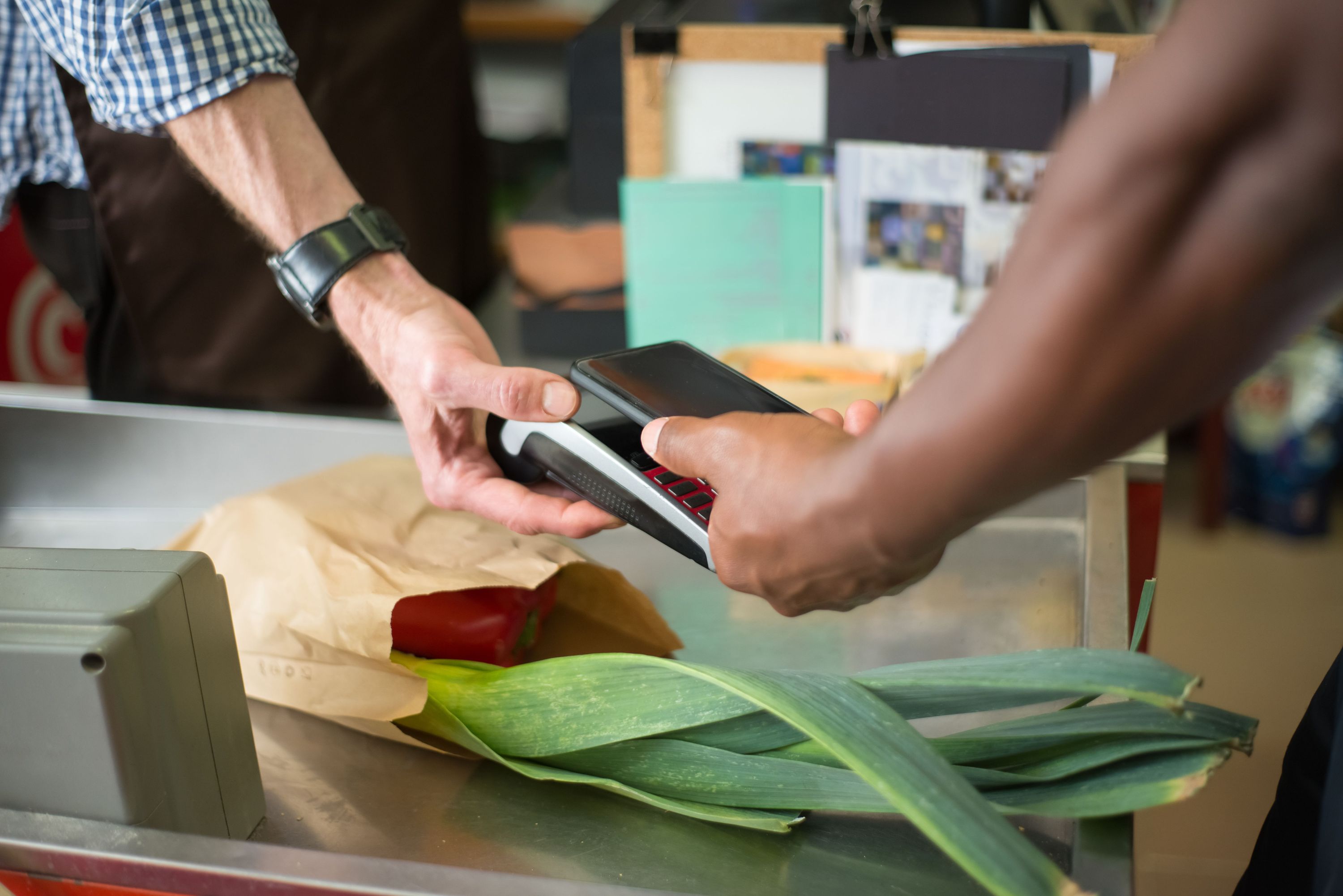 A person holding a phone at a café counter, typing a short note with one hand